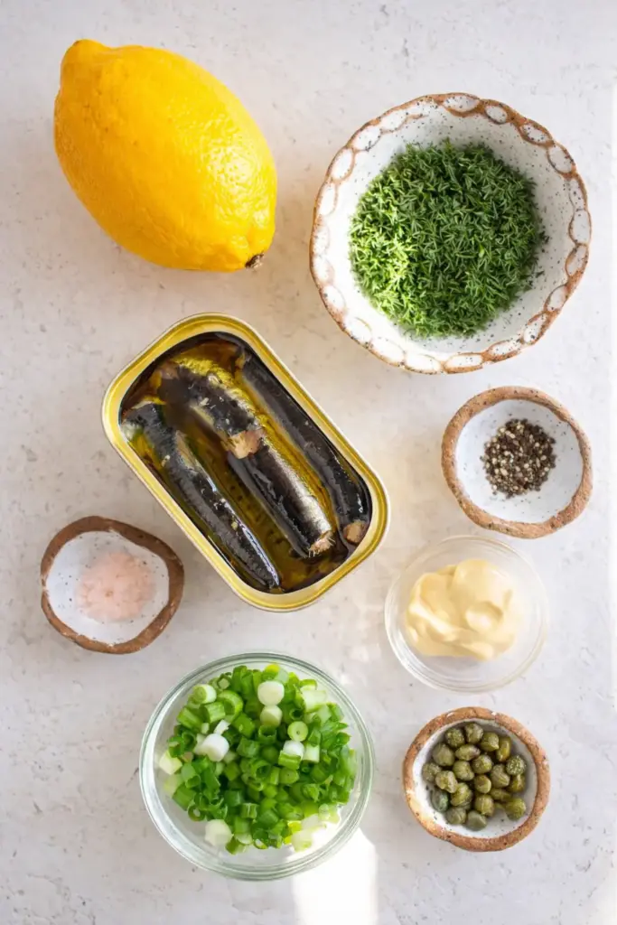 Pantry ingredients for simple sardine salad including canned sardines, lemon, dill, and mustard