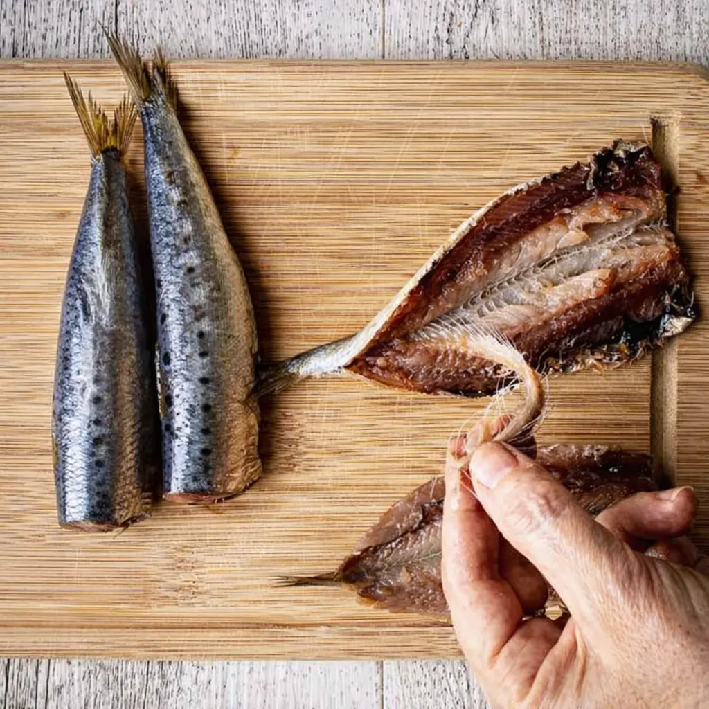 Marinating sardines in lemon garlic herbs and olive oil
