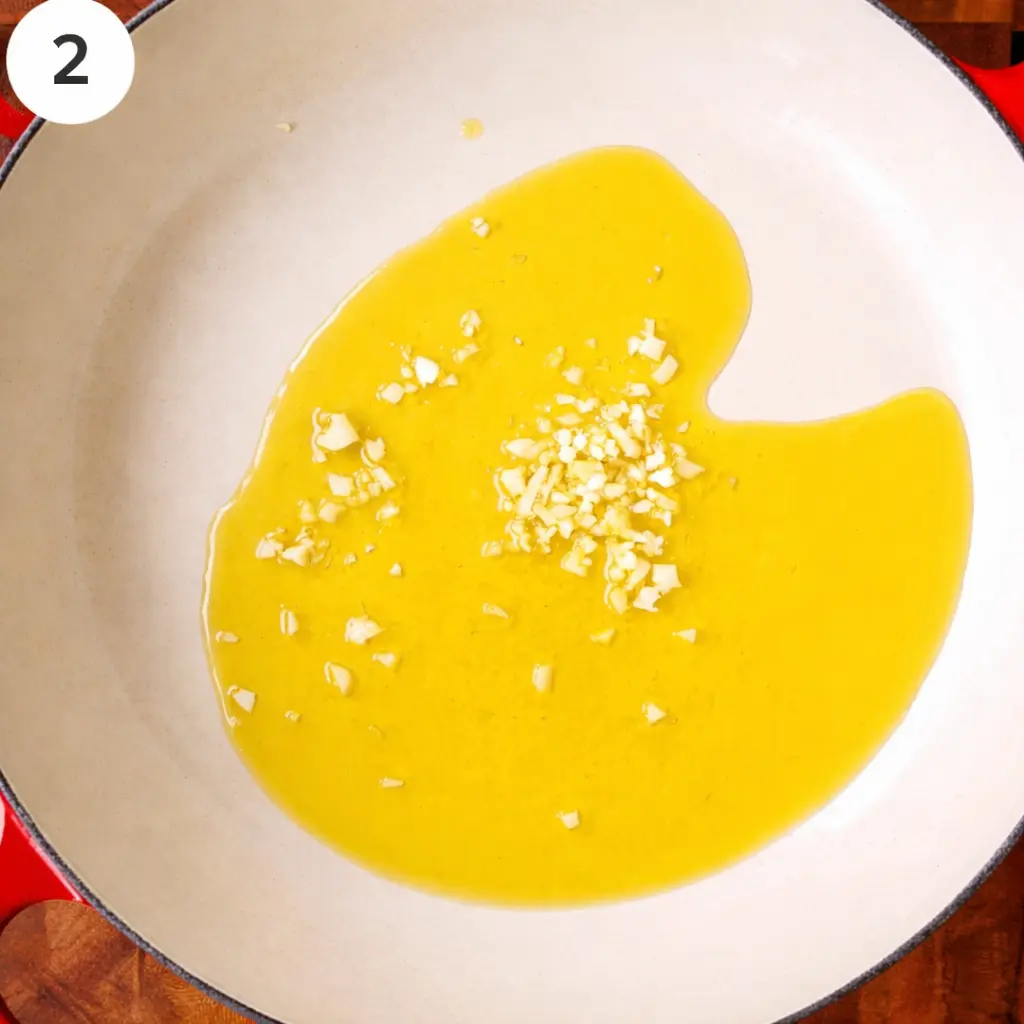 Slicing garlic cloves into cold extra virgin olive oil in a skillet