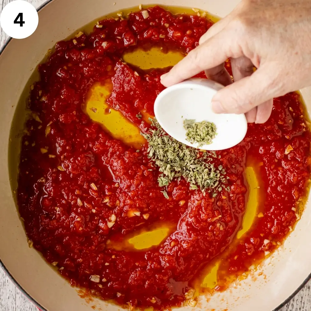 Placing tenderized beef steaks into the simmering tomato sauce
