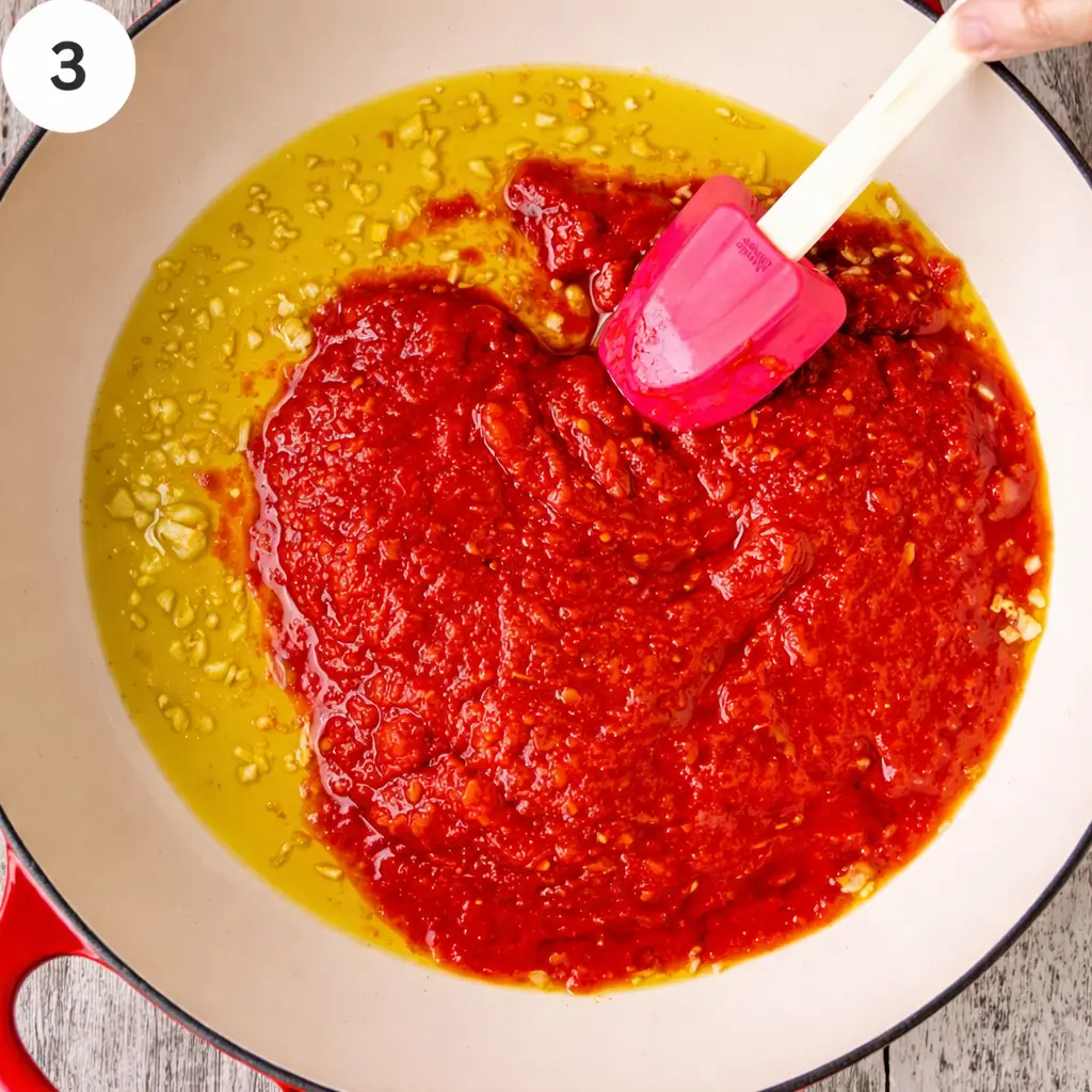 Adding crushed tomatoes, oregano, stock, and seasonings to the skillet