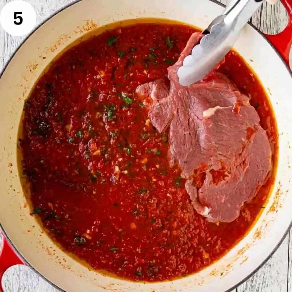 Steak pizzaiola simmering under low heat until juicy and tender