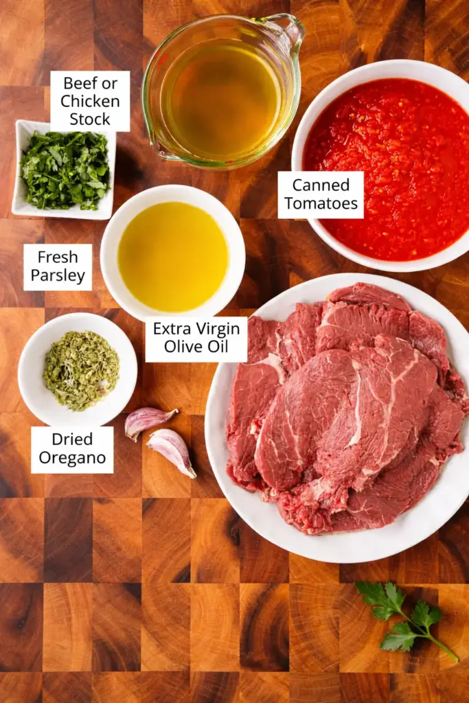 Authentic Steak Pizzaiola raw ingredients including beef steaks, crushed tomatoes, garlic, and fresh oregano