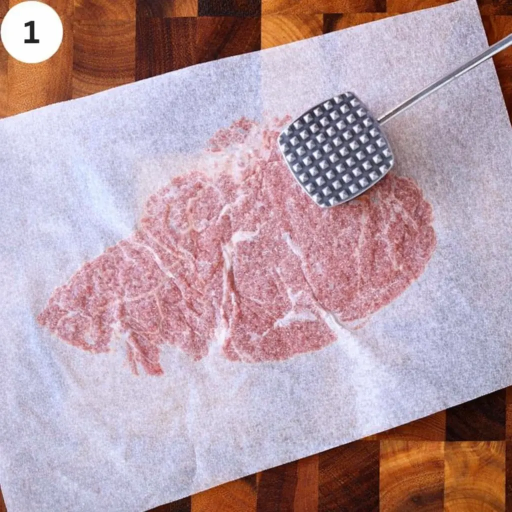 Pounding thin beef steaks with a meat mallet on a cutting board