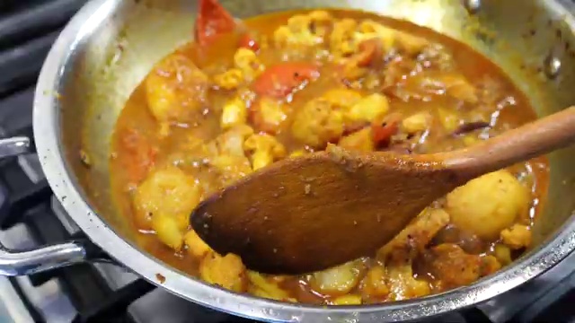 A cooked potato piece gently mashed with a spoon to naturally thicken the curry gravy