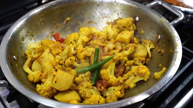Hot water, garam masala, and fresh green chilies added to the simmering cauliflower curry