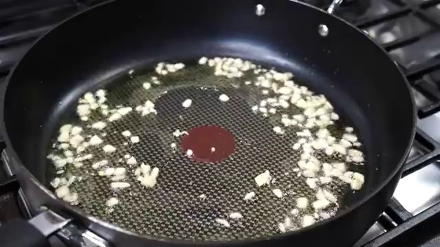 Marinated chicken thigh pieces added into the skillet with softened onions and garlic