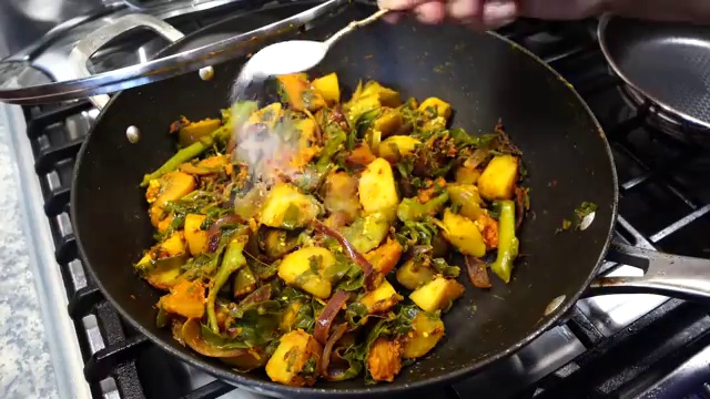 Aromatic black nigella seeds kalonji sizzling in hot cooking oil in a wide fish pan