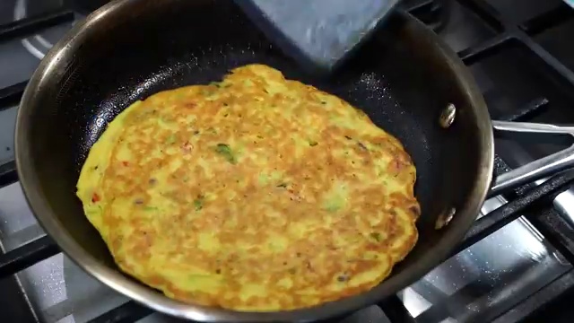 Cooking oil drizzled around the edges of the chickpea chilla before flipping