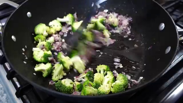 Diced red and orange bell peppers added into the pan with stir-fried broccoli