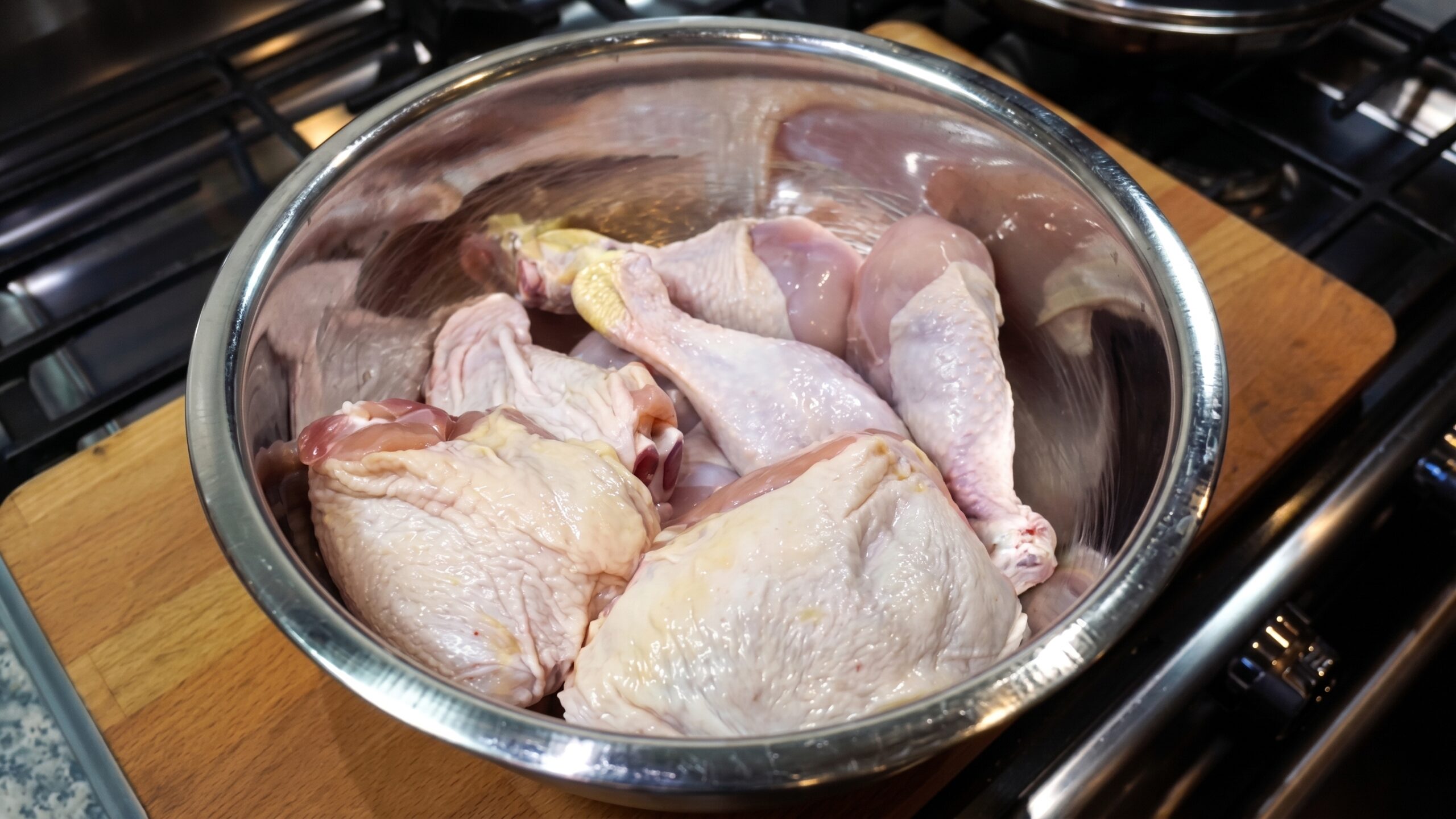 Sea salt sprinkled evenly over raw chicken thighs and drumsticks in a bowl
