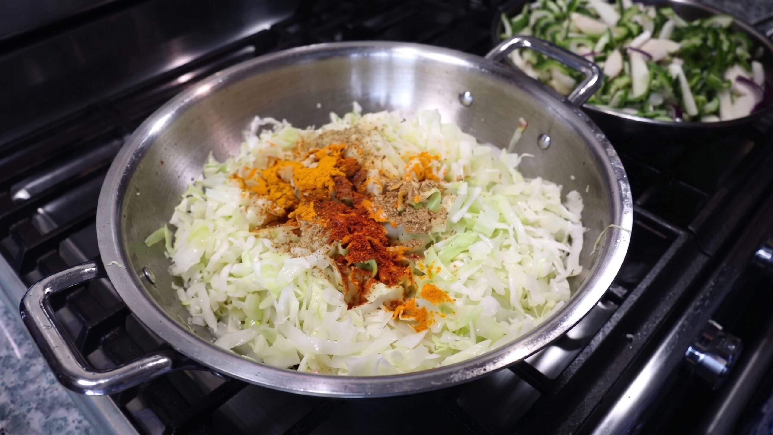 Sliced yellow onions and cubed potatoes sautéing in cooking oil in a wide skillet
