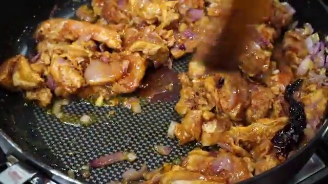 Soy sauce, vinegar, and red Kashmiri chili powder added to the cooking chicken
