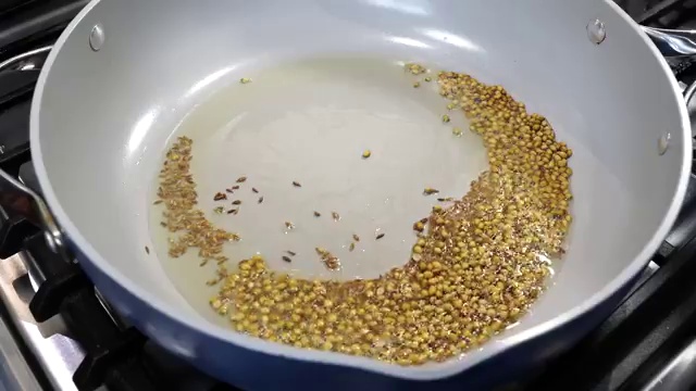 Aromatic whole spices gently roasting in a pan over low heat to release fragrant essential oils