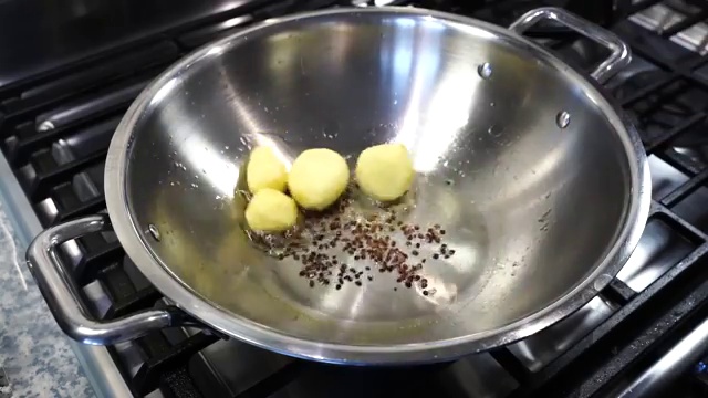 Peeled baby potatoes added to hot oil with toasted fenugreek seeds