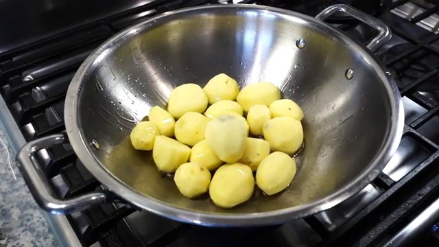 Baby potatoes frying in oil until developing golden-brown blistered spots