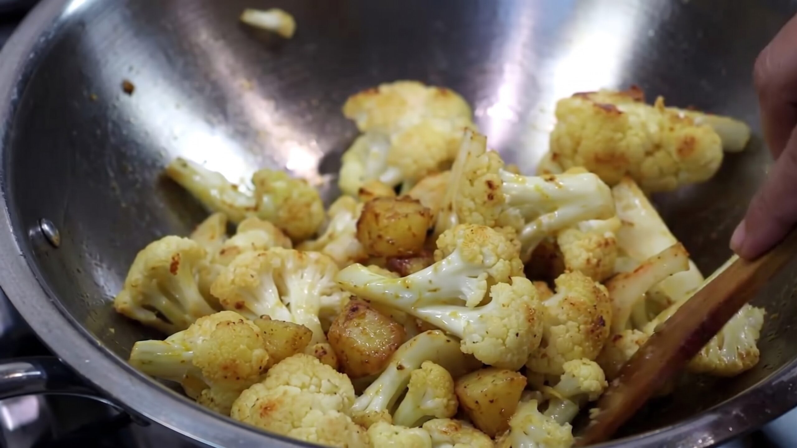 Bengali aloo fulkopir tarkari served in a bowl with golden cauliflower, potatoes, tomatoes, and peas