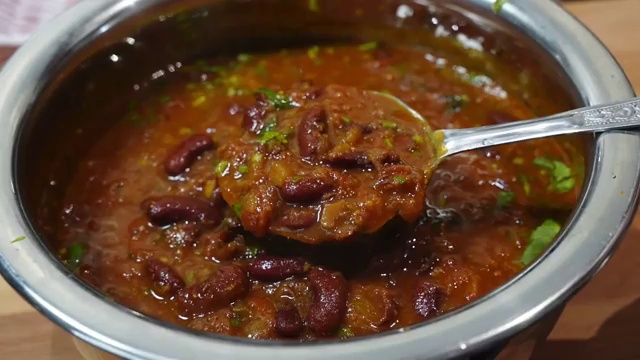 Bengali-style rajma curry served in a bowl with steamed white rice and fresh herbs