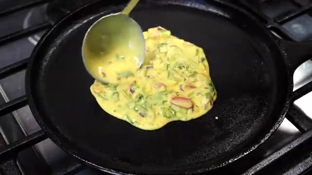 Besan chilla batter being poured and spread into a round pancake on a hot pan