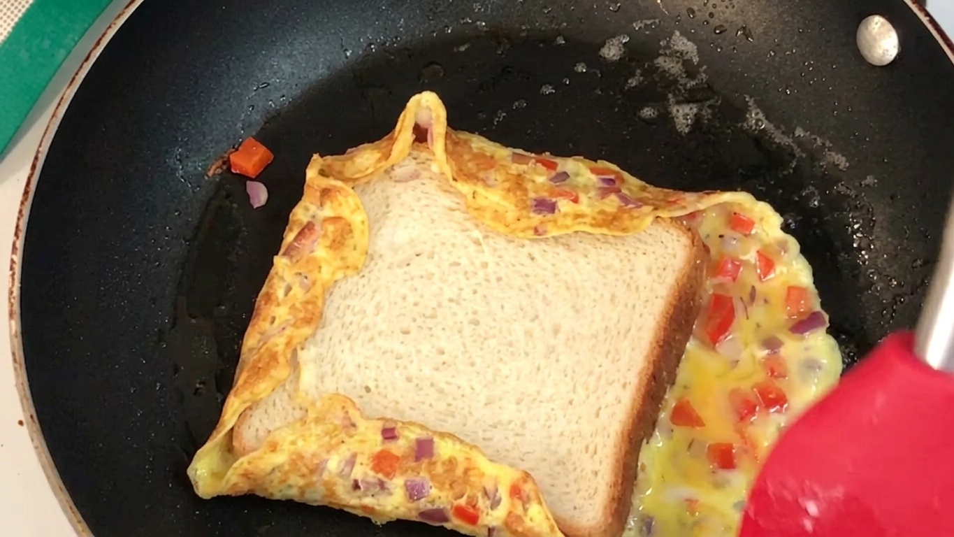 Bread omelette flipped with the buttered bread side facing down in the pan