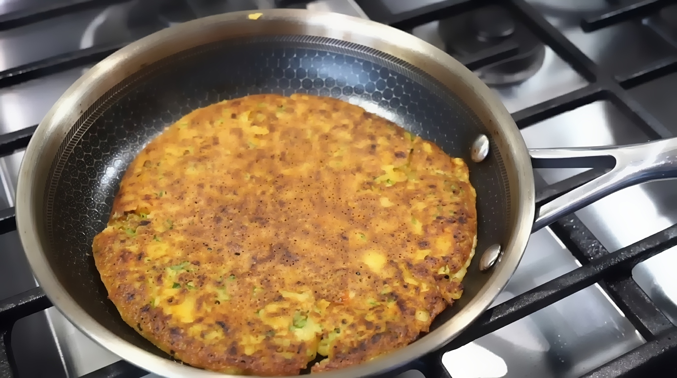 Crispy chickpea chilla served hot with creamy yogurt, fresh cucumber, onion, and bell pepper