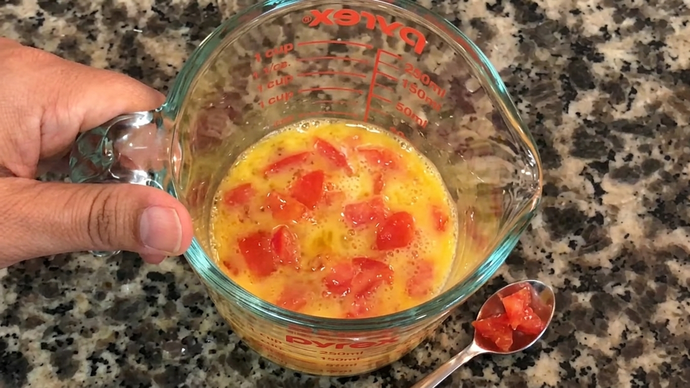 Egg whisked with milk, chopped onion, green chili, tomato, salt, and black pepper in a bowl