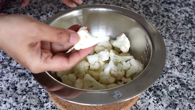 Small cauliflower florets soaking in boiling hot salted water to season and soften
