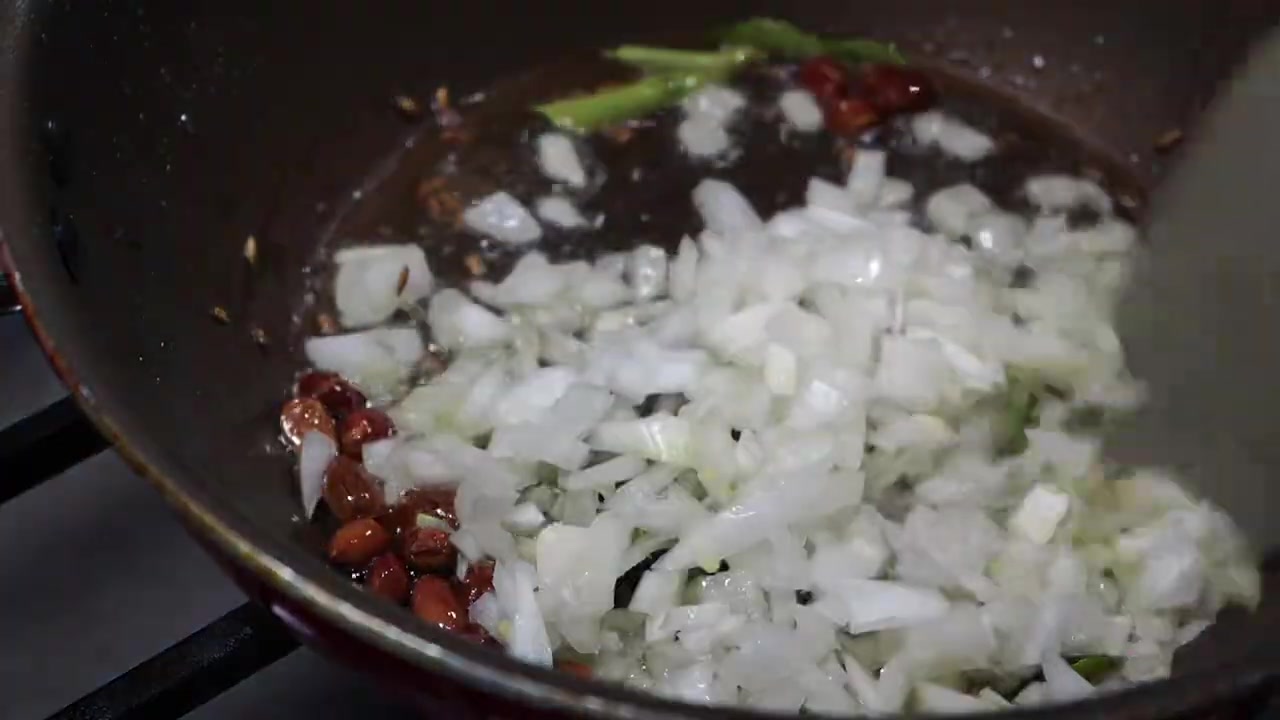 Chopped onions, ginger, and green chili cooking with the tempering spices