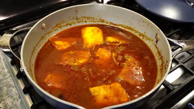Close-up texture of flaky fish fillets drenched in spicy Bengali gravy