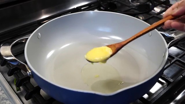 Coarsely crushed fresh garlic cloves added to sizzling cumin seeds in ghee