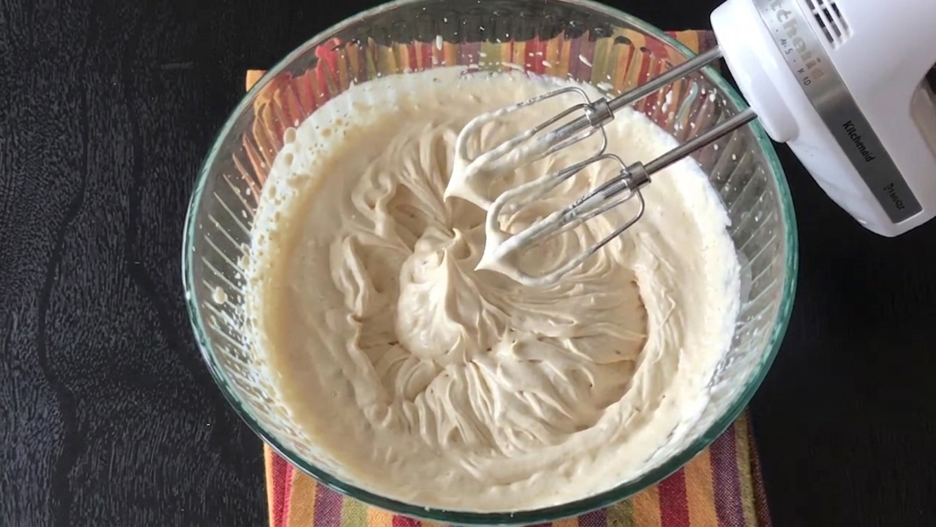Coffee-flavored heavy cream being whipped until soft peaks form