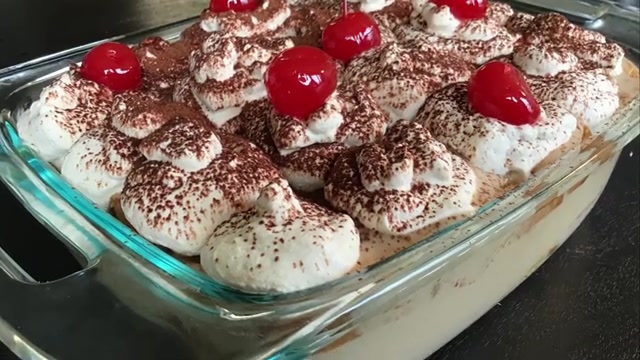 Coffee trifle pudding layered in a glass serving dish with plain cake, coffee custard, whipped cream, and cocoa powder