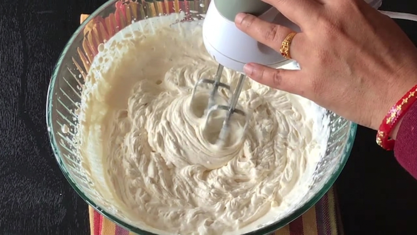 Coffee whipped cream reaching stiff peaks in a mixing bowl