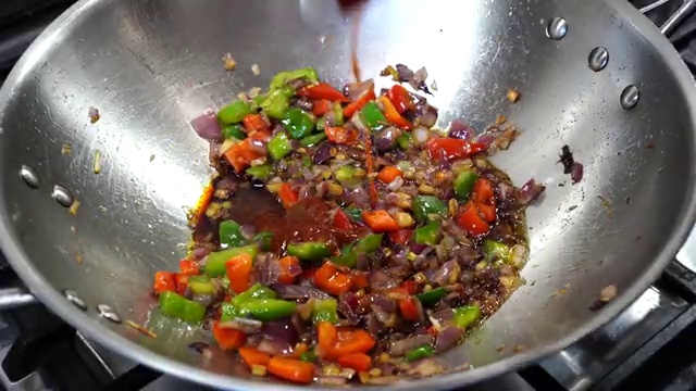 Chilled cooked rice added into the wok with the sauced cauliflower and peppers