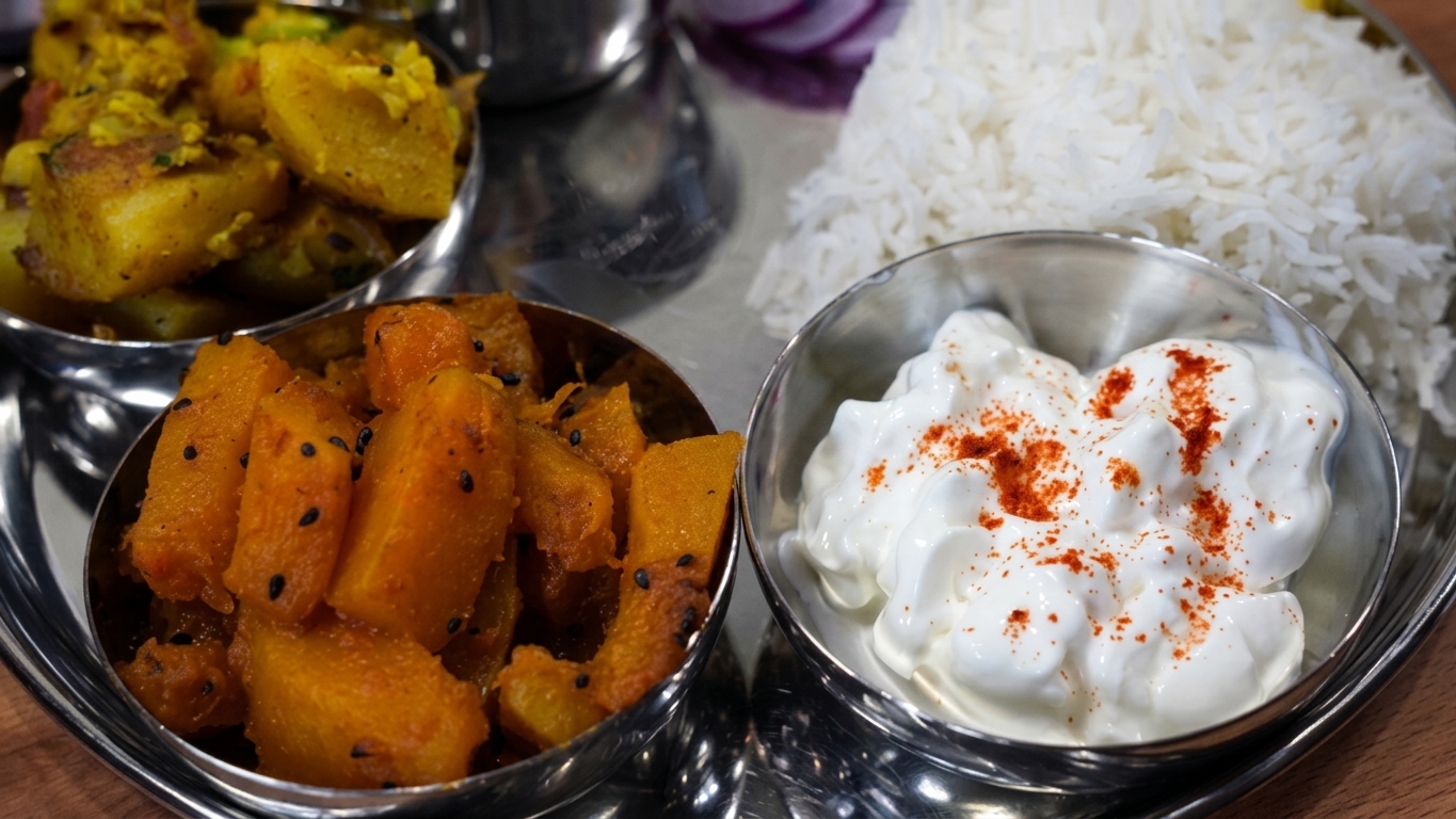 Finished Indian home-cooked plant-based feast served with rice, dal, cauliflower curry, and pumpkin