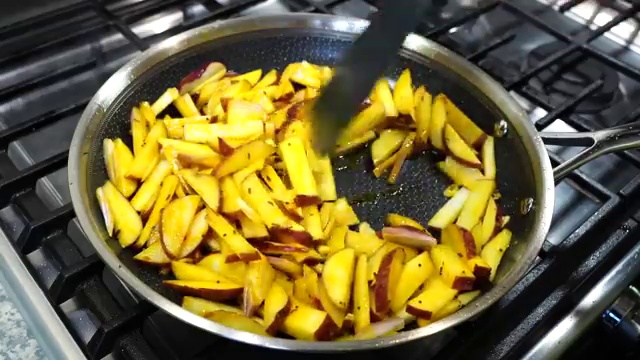 Skillet covered with a glass lid cooking the potatoes gently over low heat