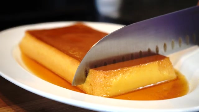 Eggless steamed mango caramel custard unmolded onto a serving plate with golden caramel flowing over the sides