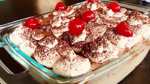 Elegant finished coffee trifle pudding with visible cake and coffee custard layers, whipped cream, cocoa powder, and cherries