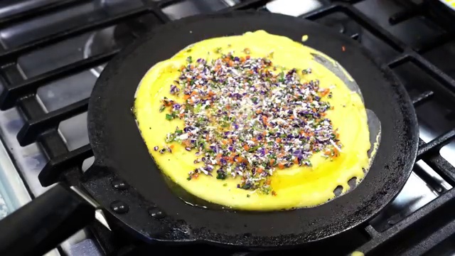 Vegetable-topped moong dal chilla lifting cleanly and releasing from the skillet surface