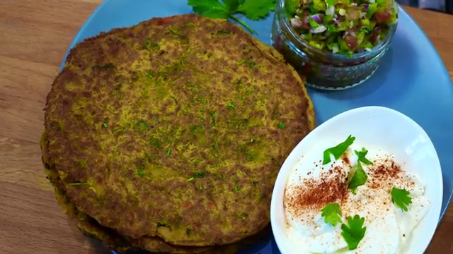 Finished golden-brown gluten-free chickpea chilla served with yogurt and fresh salad