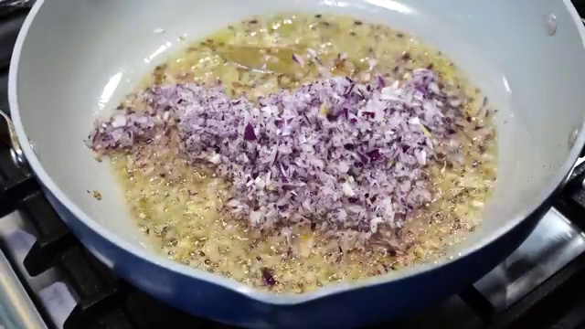 Finely chopped yellow onions cooking with cumin seeds until soft and lightly golden