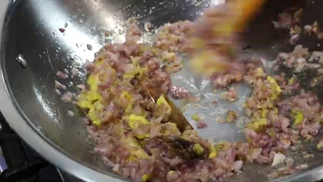 Finely chopped yellow onions added to the spiced oil and ghee in the pan