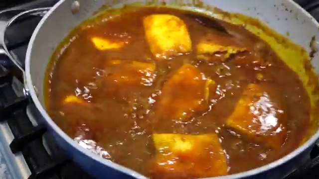 Finished Bengali Macher Jhal garnished with fresh green chilies and coriander