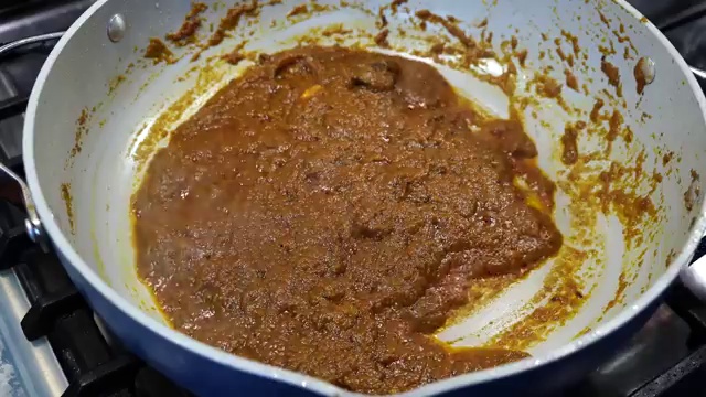 Fish curry simmering uncovered as the gravy thickens and clings to the fish