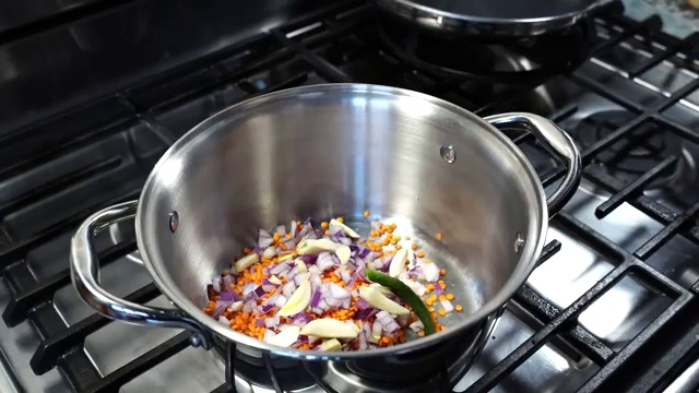 White foam being gently skimmed and removed from the surface of simmering lentils