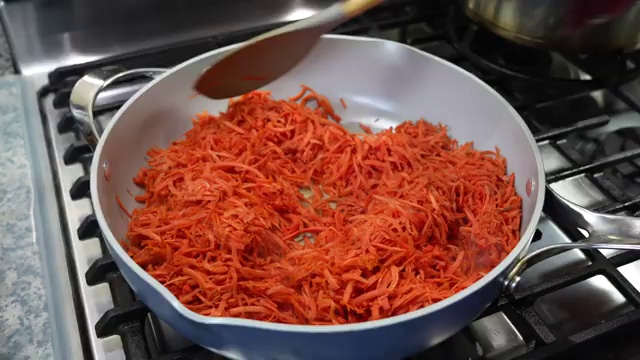Fresh juicy carrots being thoroughly washed and peeled before grating for carrot halwa