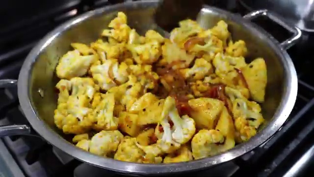 Thinly sliced yellow onions sautéing with bay leaf and whole spices in the pot