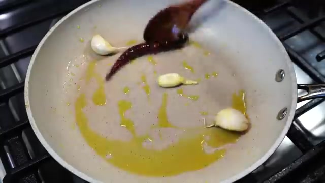 Garlic cloves, dried red chili, and toasted sesame seeds lightly frying in a pan