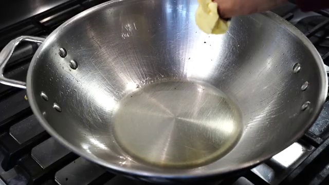 Freshly grated ginger and chopped onions added to the golden garlic in the wok