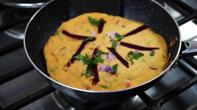 Golden crispy moonglets made with yellow moong dal, topped with colorful vegetables and fresh coriander, served with chutney